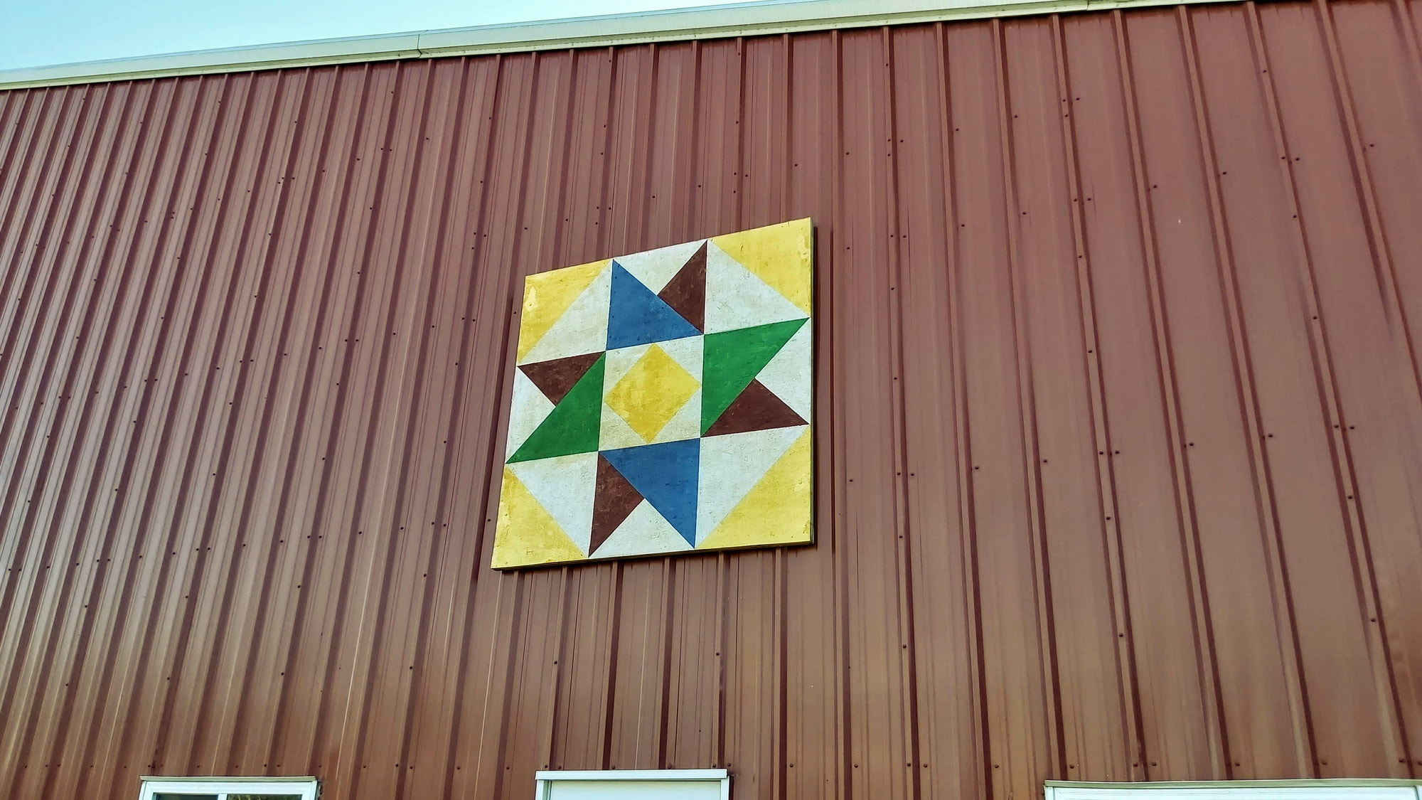 A barn quilt displayed on a Harder Farms building